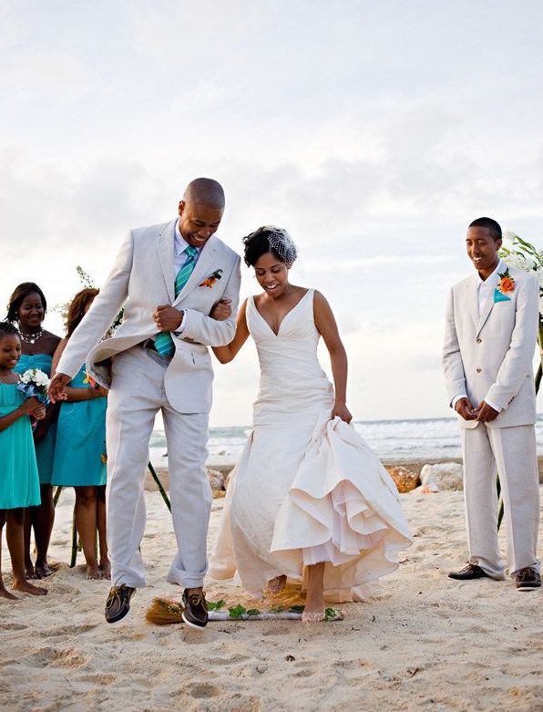 bride and groom jumping the broom on the beach